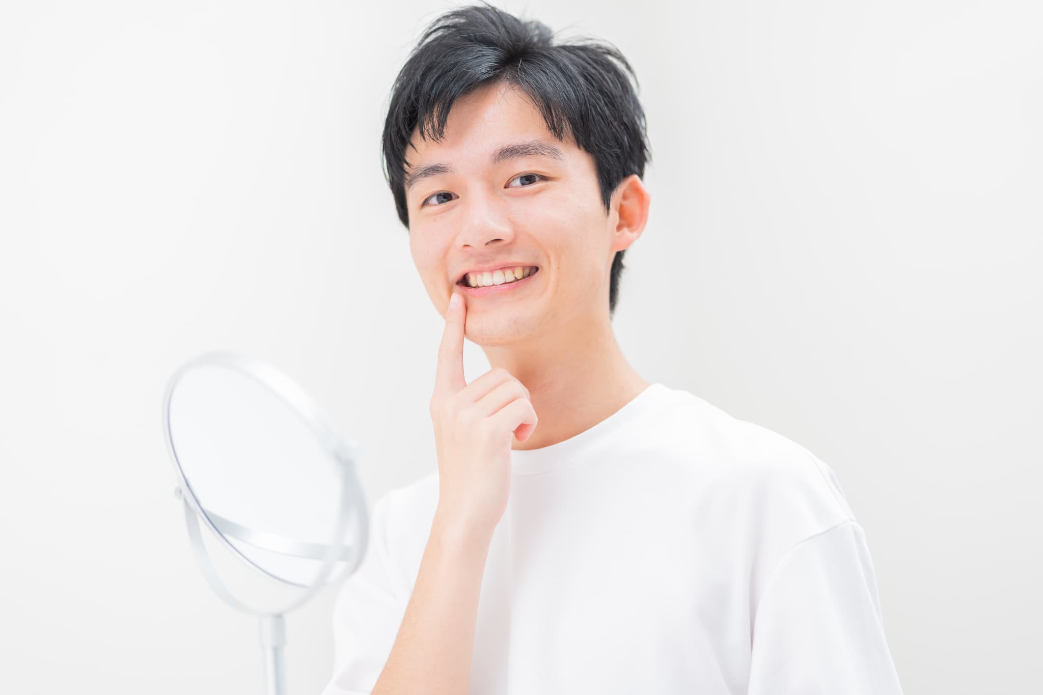 審美歯科できれいになった白い歯を鏡で見て嬉しそうな男性