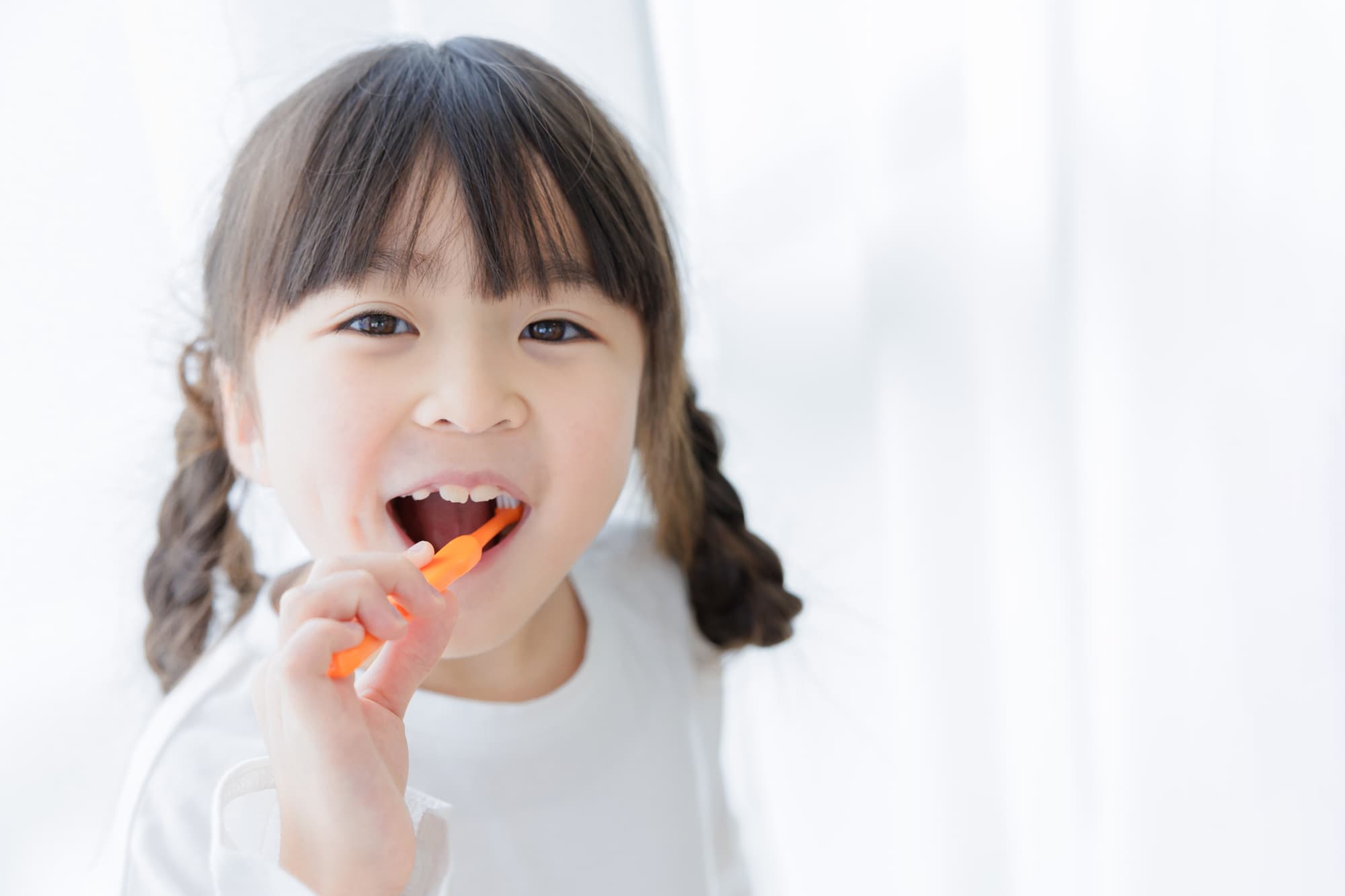 笑顔で歯磨きをする小さい女の子