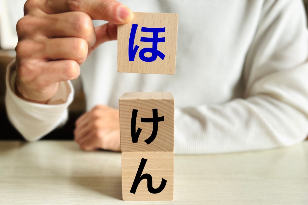 ほけんの文字の書かれたブロックを積む手