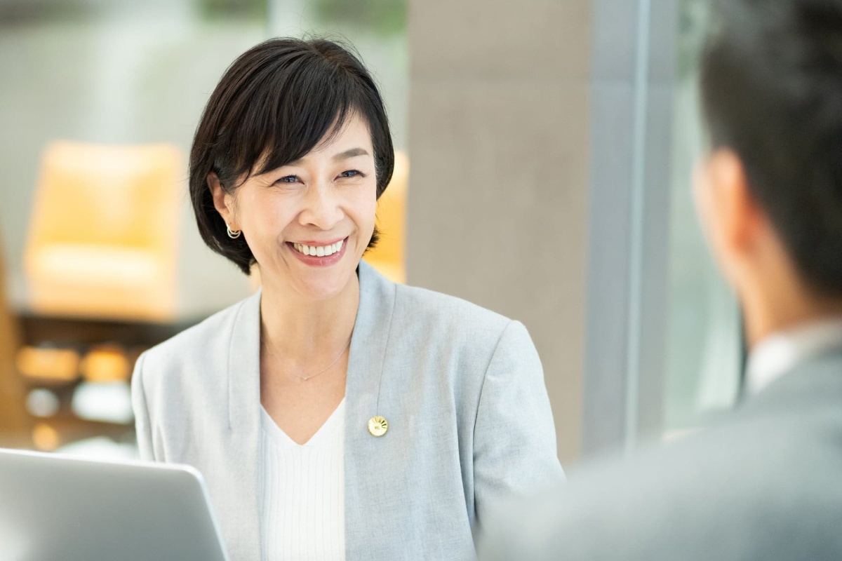PMTCをした美しい歯で接客をするミドル女性